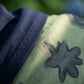 Close-up detail of the dark navy knit V-neck top fabric next to the pale sage green mesh maxi skirt, featuring an intricate navy abstract starburst pattern.