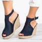Navy blue suede-like espadrille wedge sandals with a peep-toe front and adjustable ankle strap worn by a model.