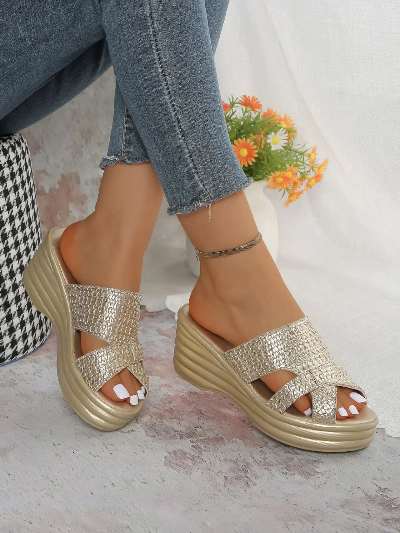 Nexaera metallic gold platform wedge sandals with a woven texture and peep-toe design, shown on a model wearing cropped denim jeans.