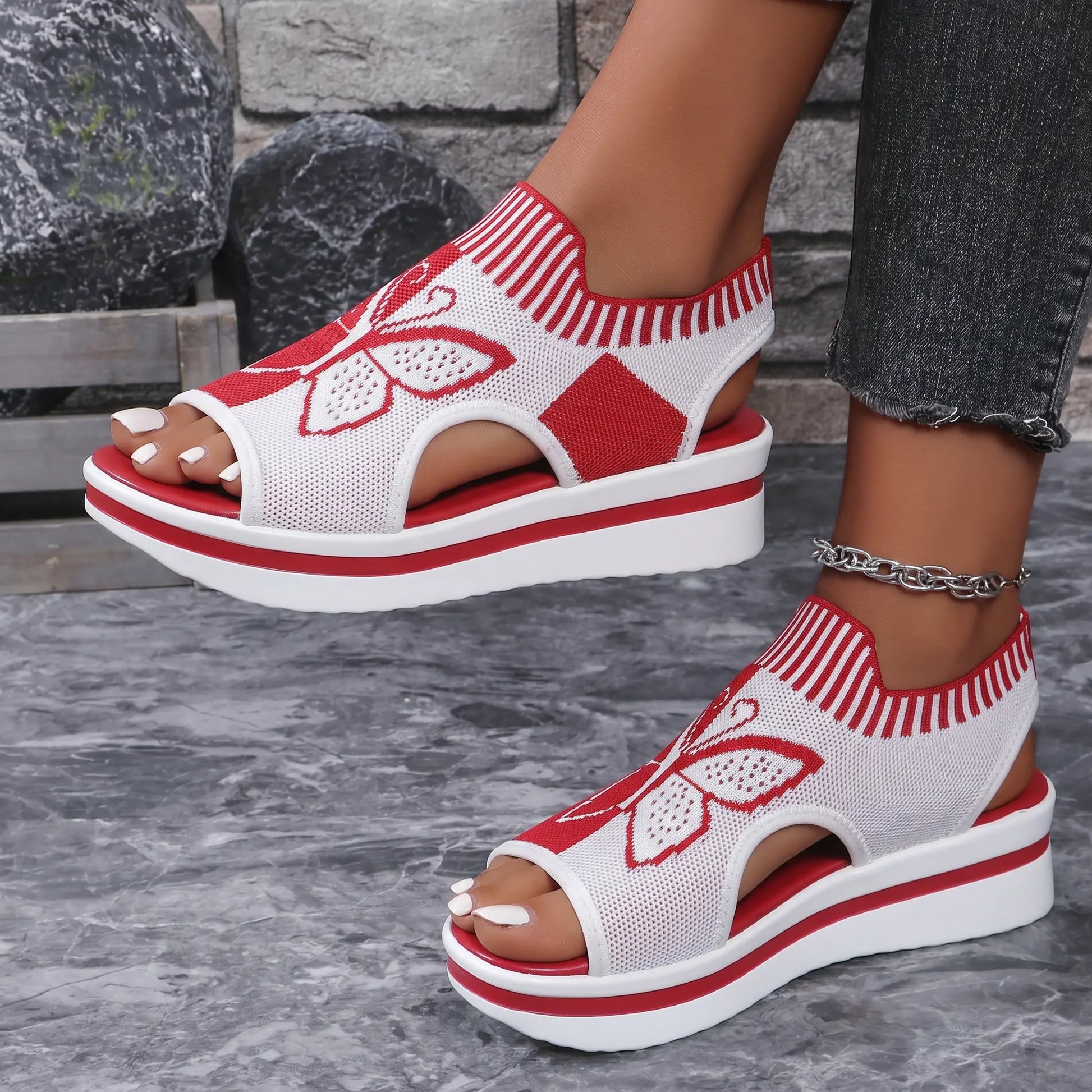 A pair of vibrant red and white Nylira women's wedge sandals worn by a model, showcasing the knitted butterfly design and peep-toe style.