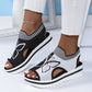 Women's black and white knit peep-toe wedge sandals with an embroidered butterfly motif and striped elastic collar, worn with white pants and an anklet.