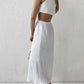 Model wearing a white sleeveless Nyssa midi dress crafted from crinkled cotton bubble crepe, featuring a round neckline and side waist cut-outs. The dress has a straight silhouette and falls to mid-calf.