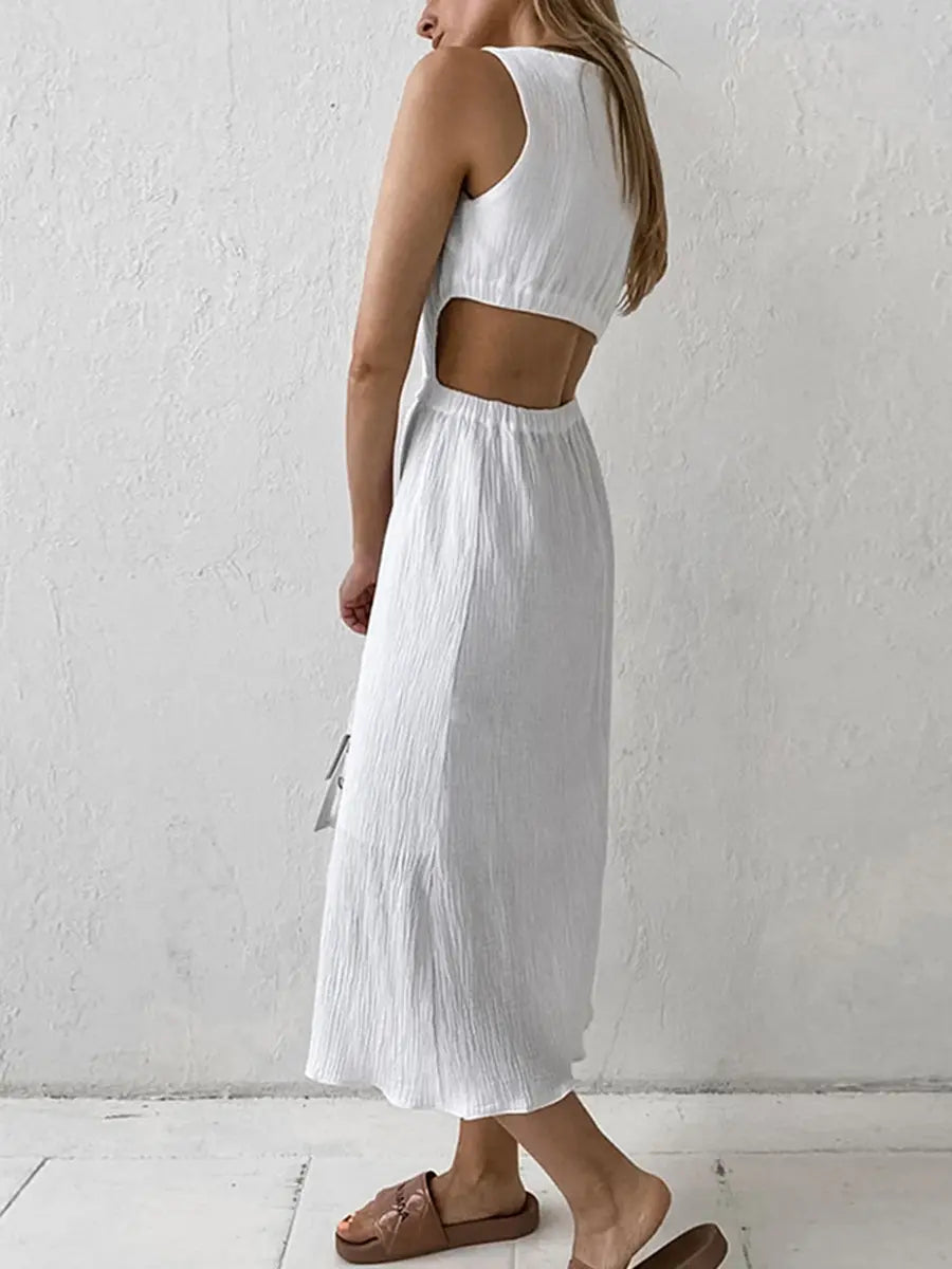 Model wearing a white sleeveless Nyssa midi dress crafted from crinkled cotton bubble crepe, featuring a round neckline and side waist cut-outs. The dress has a straight silhouette and falls to mid-calf.