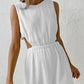 Nyssa white cotton crepe sleeveless midi dress featuring waist cut-outs and a round neckline, displayed on a model against a textured studio background.