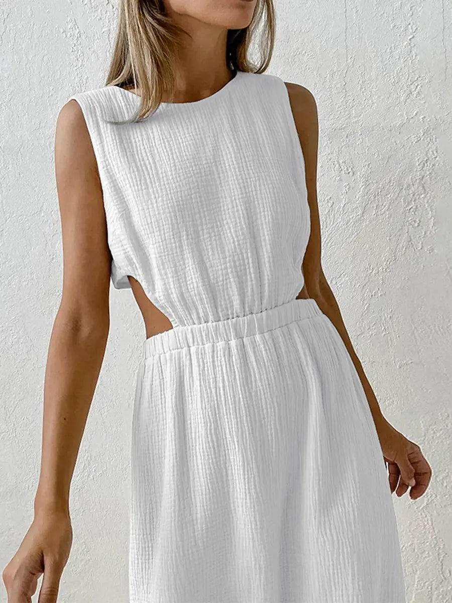 Nyssa white cotton crepe sleeveless midi dress featuring waist cut-outs and a round neckline, displayed on a model against a textured studio background.