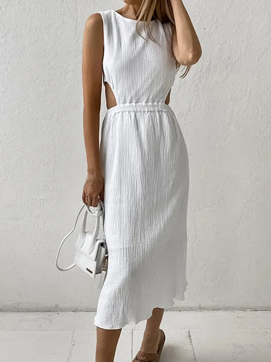 A white sleeveless midi dress with distinctive waist cut-outs and a crinkled bubble crepe texture is showcased on a model against a subtly textured wall.