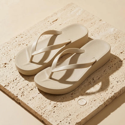 Oatmeal beige platform wedge thong sandals with textured honeycomb footbeds and flexible Y-straps, presented on a light stone slab.
