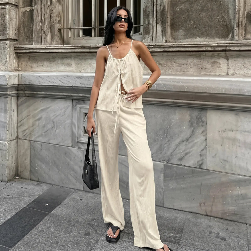 A woman models an elegant bohemian linen set in oatmeal beige, featuring a halter tie-top and flowy wide-leg trousers, styled for summer.