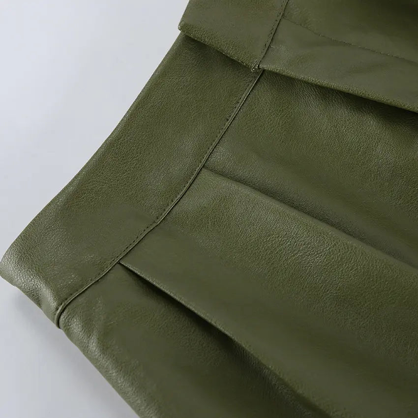 Close-up of olive green faux leather shorts showcasing texture, sharp front pleats, and precise stitching on the waistband.