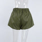 Olive green high-waist faux leather shorts with a distinctive balloon silhouette and prominent front pleats, displayed on a mannequin.
