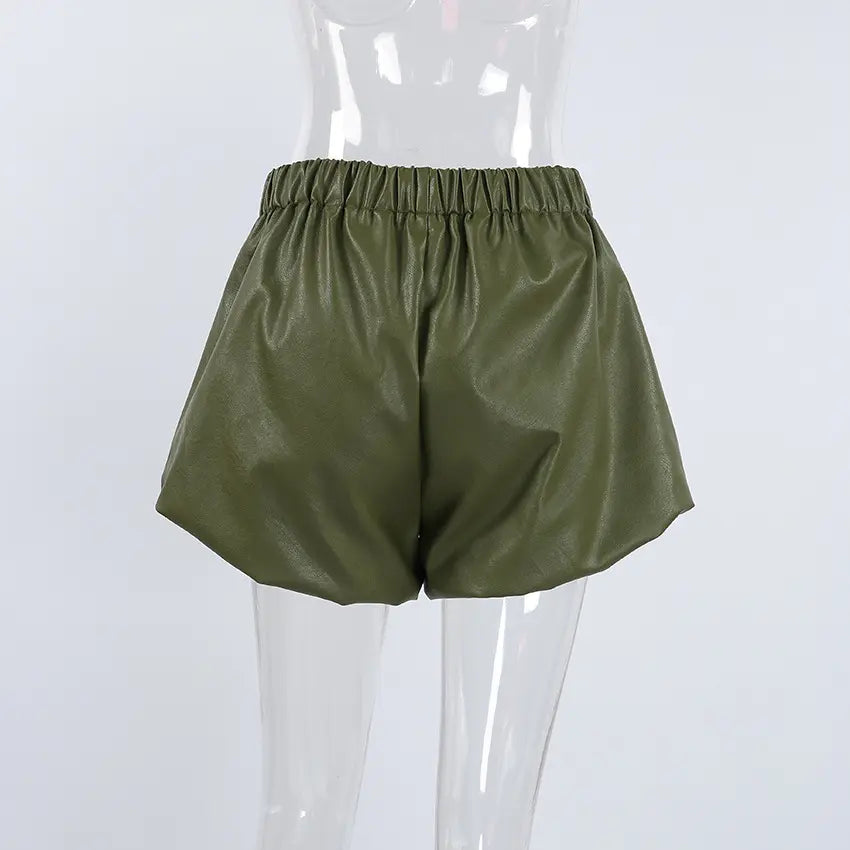 Olive green high-waist faux leather shorts with a distinctive balloon silhouette and prominent front pleats, displayed on a mannequin.