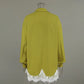 Back view of an olive green, oversized, long-sleeved linen-blend shirt featuring delicate white floral lace trim along the hem, presented on a mannequin.