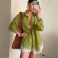 Model in an olive green linen-blend set with an oversized lace-trimmed shirt and wide-leg shorts, styled with accessories.