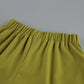Close-up detail of olive green linen-blend shorts waistband with elastic gathering, showcasing fabric texture and relaxed fit.