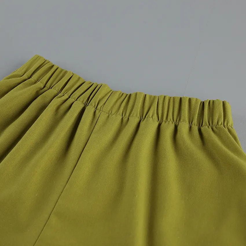 Close-up detail of olive green linen-blend shorts waistband with elastic gathering, showcasing fabric texture and relaxed fit.