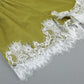 Close-up detail of delicate white floral lace trim on the hem of an olive green linen-blend shorts, showcasing artisanal craftsmanship and romantic allure.