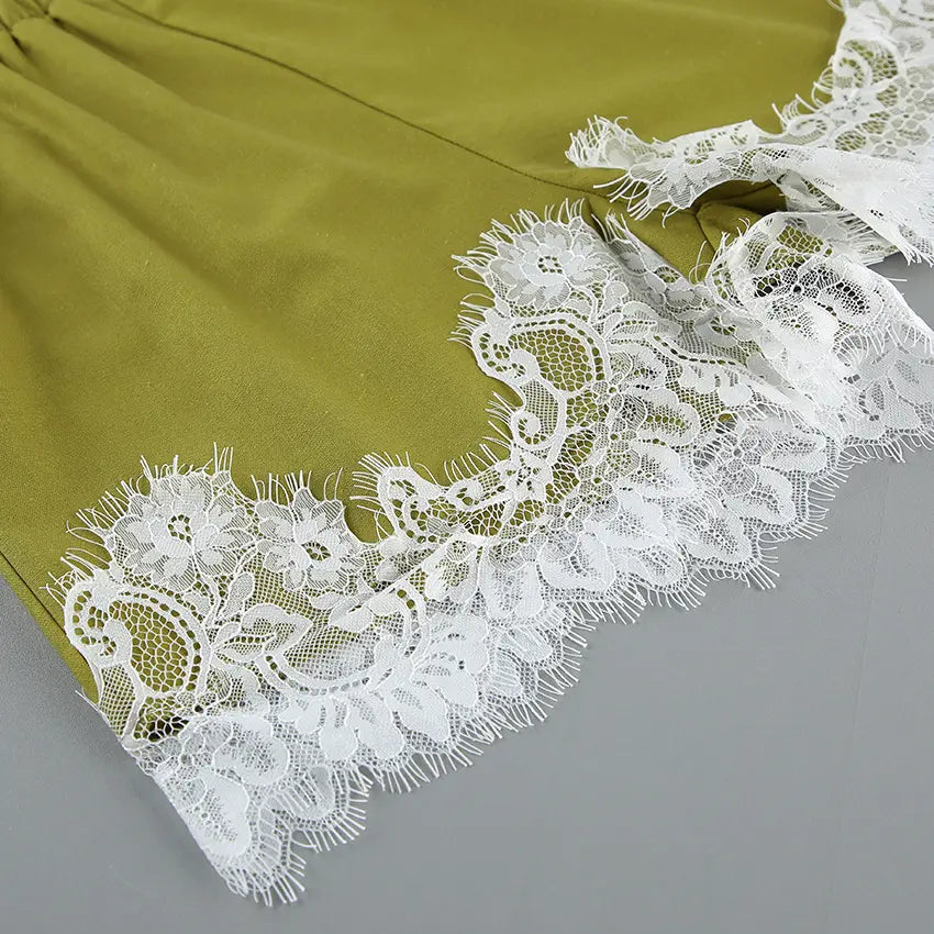 Close-up detail of delicate white floral lace trim on the hem of an olive green linen-blend shorts, showcasing artisanal craftsmanship and romantic allure.