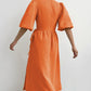 Orange crinkled cotton gauze midi wrap dress with short puff sleeves and tie waist, shown from the back view on a model against a white background.