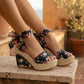 Oruzen black floral espadrille platform wedge sandals, worn on feet, with a peep-toe upper and romantic ribbon ankle ties. Displayed outdoors.