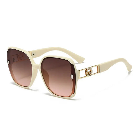 Oversized square butterfly sunglasses in cream with gradient brown and pink lenses, featuring decorative gold geometric hardware with rhinestones on the temples.