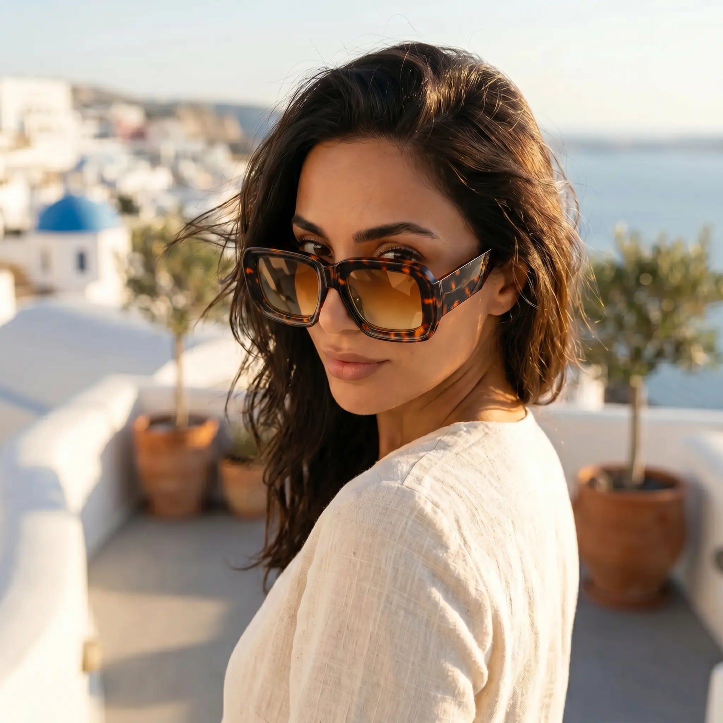 Elegant woman wearing Kyzeth oversized square tortoiseshell sunglasses with gradient amber lenses, posing outdoors in a sunny setting.