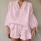 Pale pink linen-blend loungewear set featuring a loose V-neck blouse with voluminous lantern sleeves and ruffled hem shorts, worn by a model.