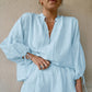 Model wearing a pale pink linen-blend two-piece set featuring a loose V-neck blouse with drawstring tie and voluminous lantern sleeves, paired with high-waisted ruffled hem shorts.