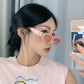 Woman wearing elegant pink cat-eye sunglasses with gold interlocking BB logo hardware and tinted orange-pink lenses, styled as a fashion accessory.