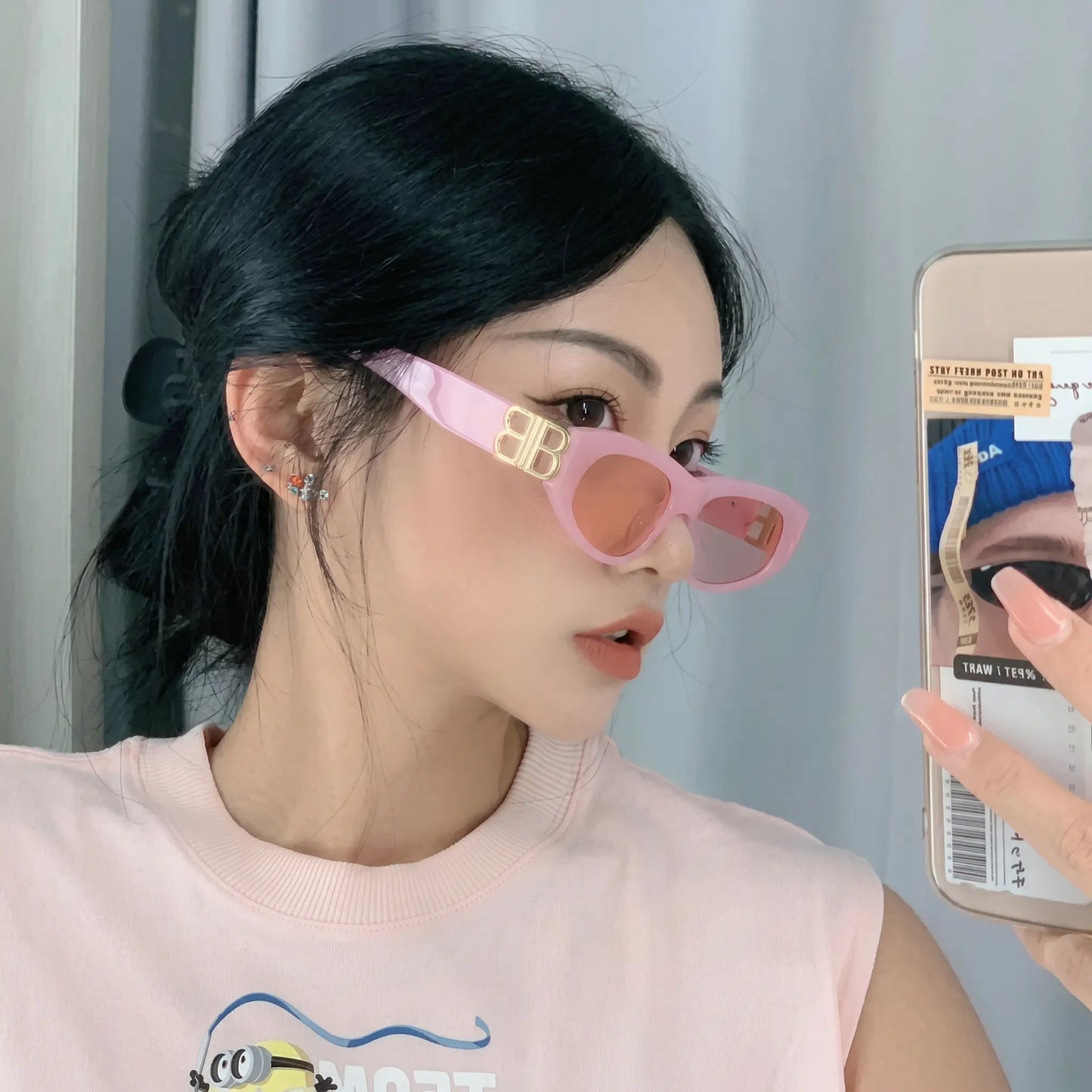 Woman wearing elegant pink cat-eye sunglasses with gold interlocking BB logo hardware and tinted orange-pink lenses, styled as a fashion accessory.