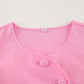 Close-up of a vibrant pink cotton button-up top featuring fabric-covered buttons and a flattering round neckline with a size label.