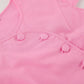 Close-up detail of a vibrant pink cotton two-piece set, showcasing matching fabric-covered buttons on the rounded neckline and front placket of a cropped top and midi skirt.