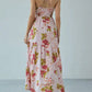 Back view of a Bohemian Floral Maxi Dress in pink gingham, featuring a smocked bodice, halter neckline with cross-back straps, and a flowing tiered skirt.