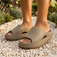 Kynso Platform Lounge Slides in Gravel Khaki molded EVA worn on feet, standing on a light pebbled garden path.