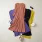 Flat-lay view of a rose pleated V-neck midi dress with fabric buttons, layered over purple, black, and yellow variants. Styled with white flats and handbags on a light background.