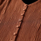 Close-up of the Zethrin pleated midi dress in Terracotta Red, highlighting the finely textured micro-pleats and matching fabric-covered buttons along the V-neckline placket.