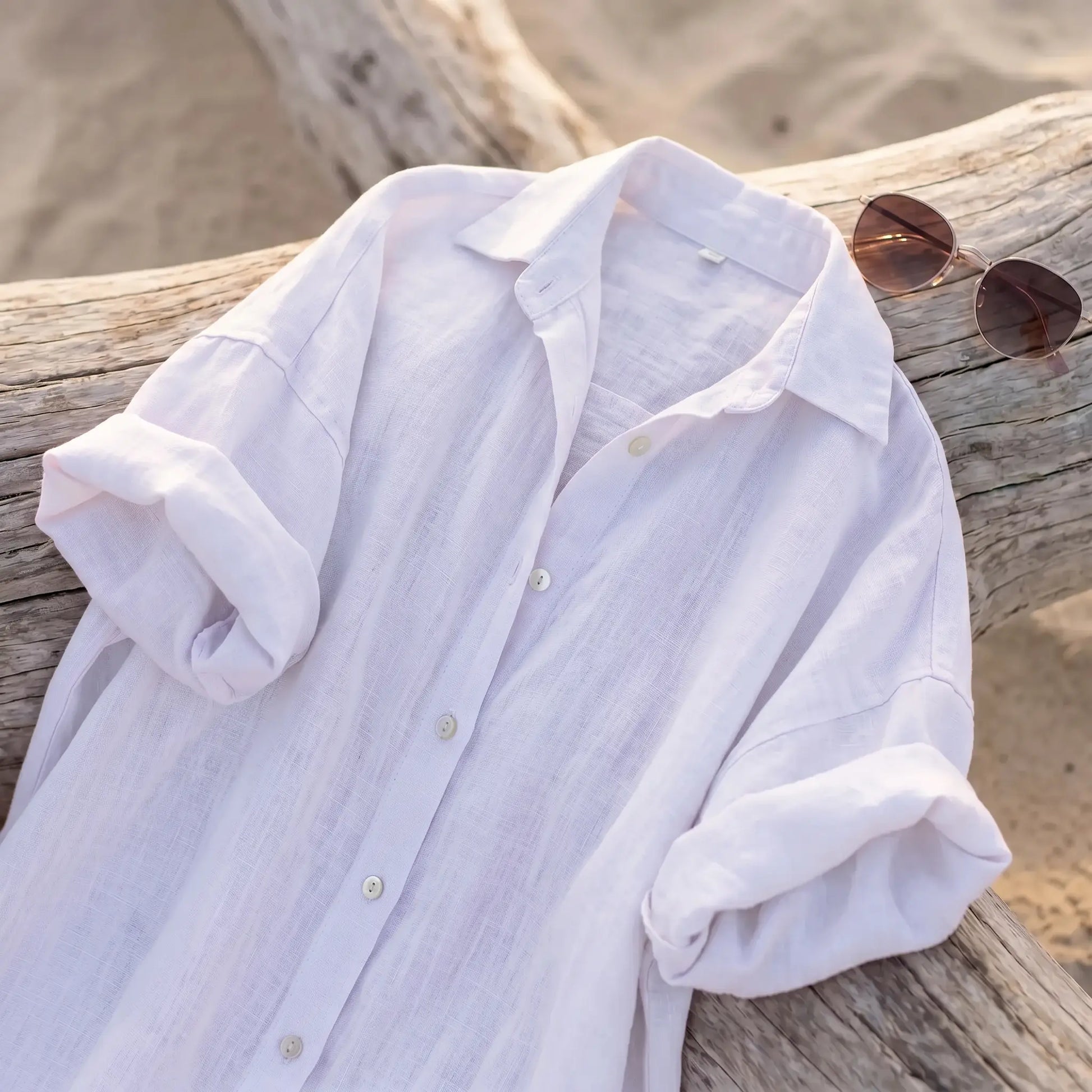 Pristine White linen blend maxi shirt dress with classic collar, pearl-toned buttons, and rolled sleeves, draped on beach driftwood.