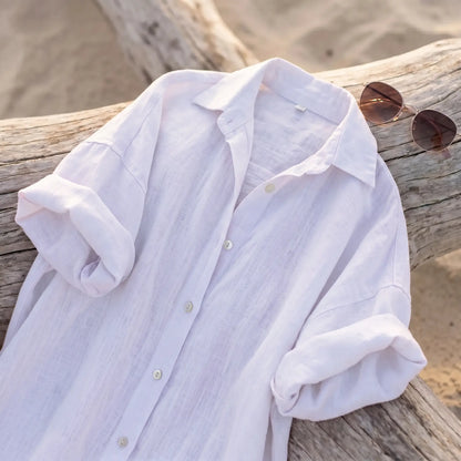 Pristine White linen blend maxi shirt dress with classic collar, pearl-toned buttons, and rolled sleeves, draped on beach driftwood.