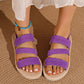 Purple woven elastic strap flat sandals with a fish-mouth open toe, styled with a turquoise anklet and a flowing white garment.