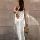 Qyren ivory white flowing halter resort maxi dress, worn by a model from the back. Shows gathered halter neckline, delicate straps, open back, and sweeping A-line silhouette.