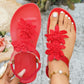 Bohemian red flat sandals for women, featuring layered fabric floral appliqués and a comfortable elasticated slingback strap, shown on a foot with white-toe nails.