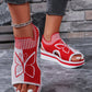 Red and white women's knit wedge sandals with a detailed butterfly motif, peep-toe design, and slingback strap, worn by a model with dark denim jeans.