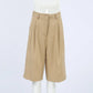 Rhyza women's high-waisted, wide-leg Bermuda shorts in warm khaki, shown front view. Features tailored pleats, a smooth waistband with button closure, and a finished cuffed hem.