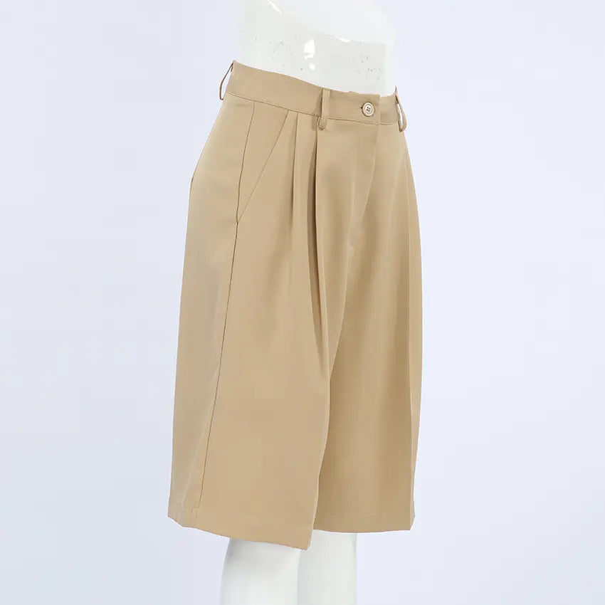 Rhyza Women's Tailored Bermuda Shorts in Khaki, featuring a high waist, wide leg, front pleats, and cuffed hem, shown from a three-quarter view on a white background.