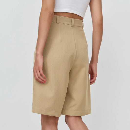 Back three-quarter view of Rhyza tailored khaki Bermuda shorts on a model, showcasing the high waist, wide leg, and cuffed hem.