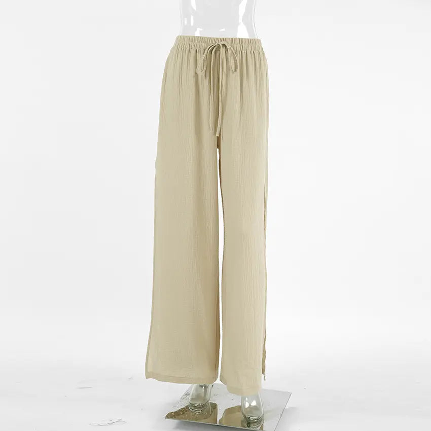 High-waisted wide-leg trousers in a breathable, slubbed oat-beige cotton fabric, featuring a drawstring waist and deep side slits for a flowing silhouette.