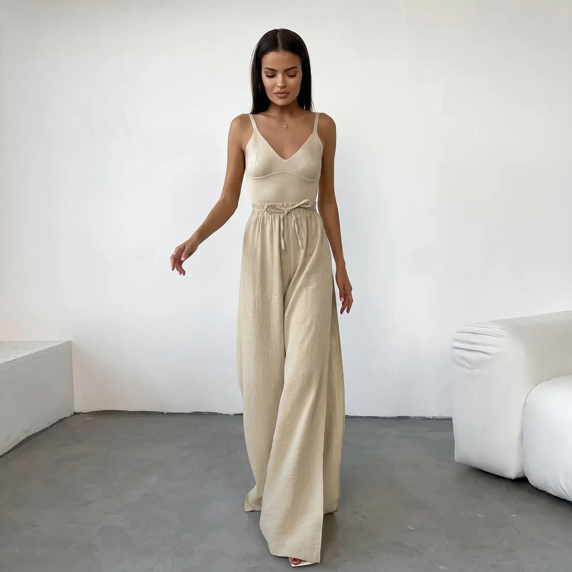 Rhyzen high-waisted wide-leg trousers in textured oat-beige breathable cotton, worn by a model with deep side slits and a drawstring waist. Shot from the front in a studio.