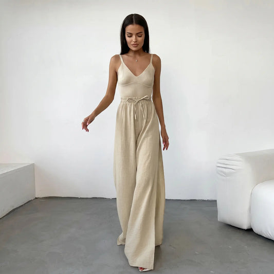 Rhyzen high-waisted wide-leg trousers in textured oat-beige breathable cotton, worn by a model with deep side slits and a drawstring waist. Shot from the front in a studio.