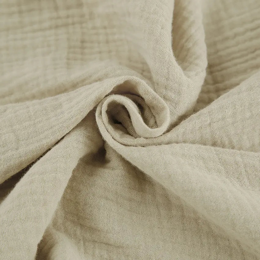 Close-up of Rhyzen wide-leg trousers fabric, showcasing the breathable, slubbed oat-beige cotton texture and flowing drape.