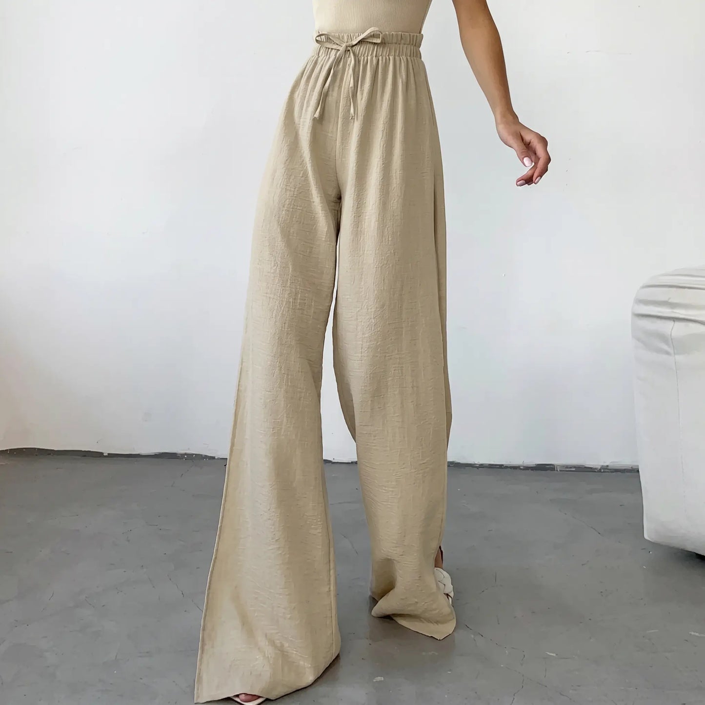 High-waisted, wide-leg trousers in textured oat-beige breathable cotton, featuring a drawstring waist and dramatic deep side slits up to the thigh.