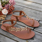 Rivenia Bohemian woven flat sandals in warm brown, featuring a T-strap with carved wood-effect floral and circular embellishments and an elasticized ankle strap.